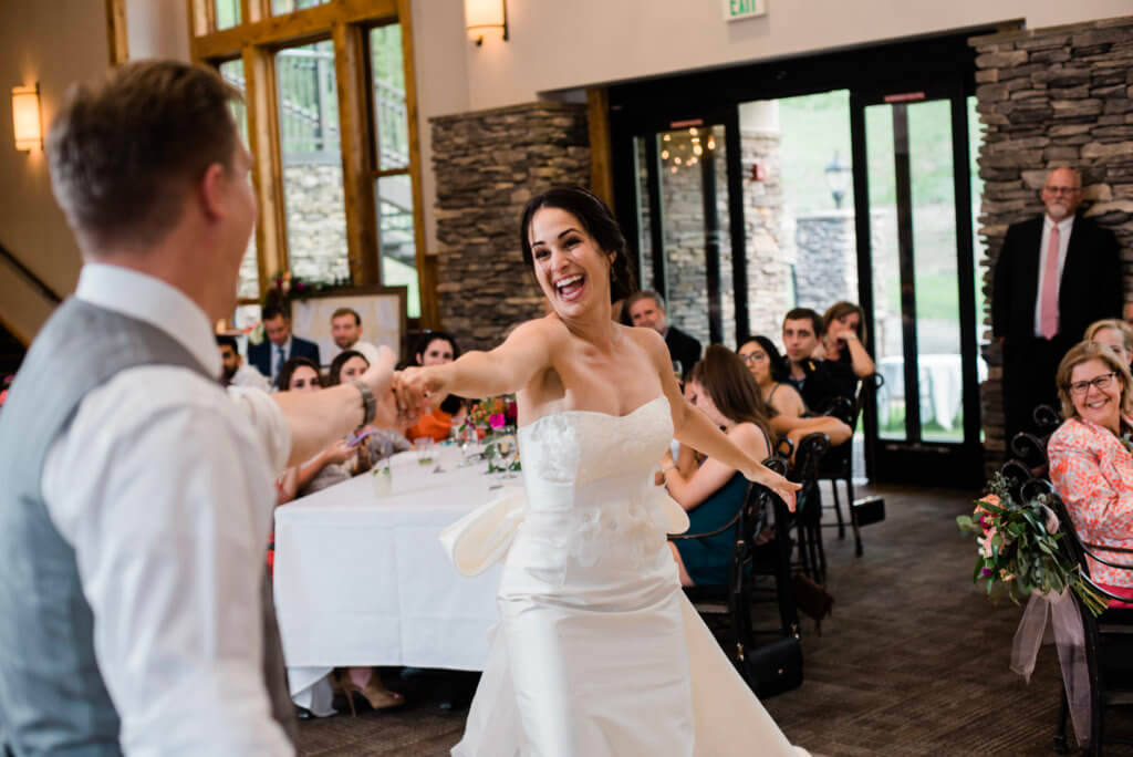 A bride smiling and dancing with her groom at their wedding.